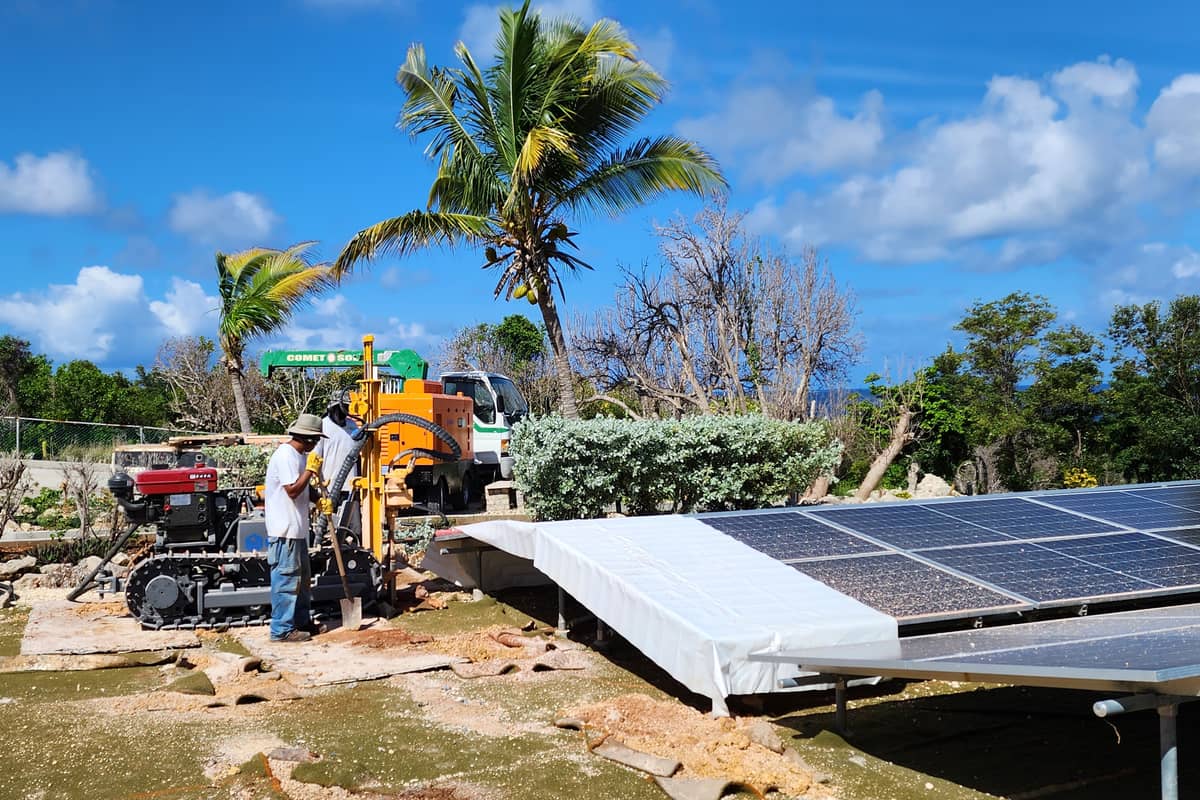 Comet Solar crew drilling and setting footings for a ground-mount solar array