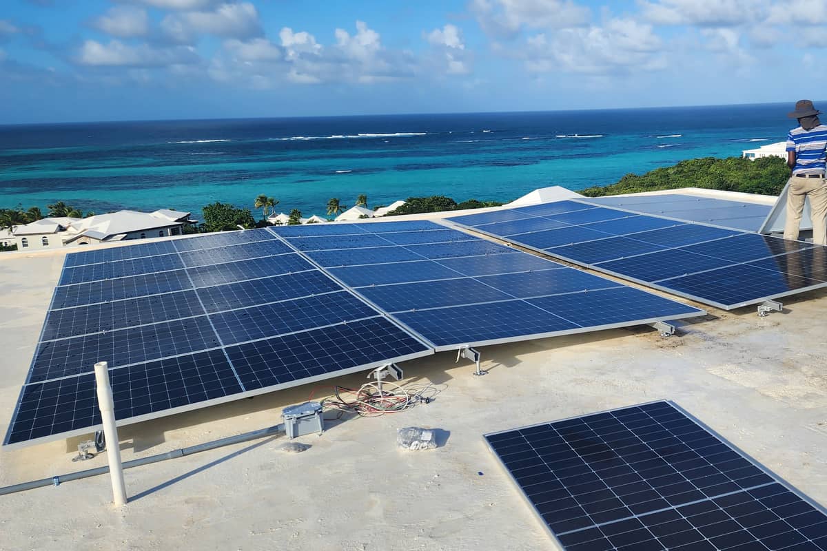 Comet Solar installers setting panels on a rooftop above the Caribbean sea